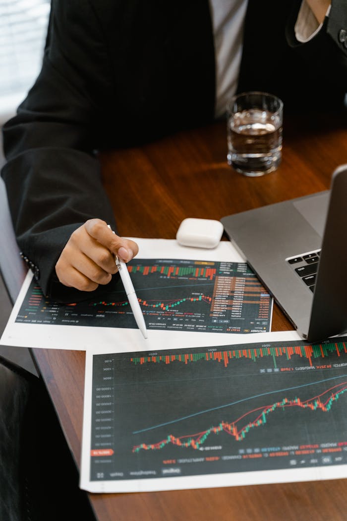 Close-up of a business analyst reviewing printed financial graphs and charts at an office desk.